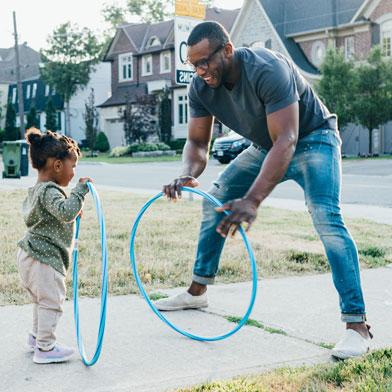 a dad playing with his daughter in the driveway